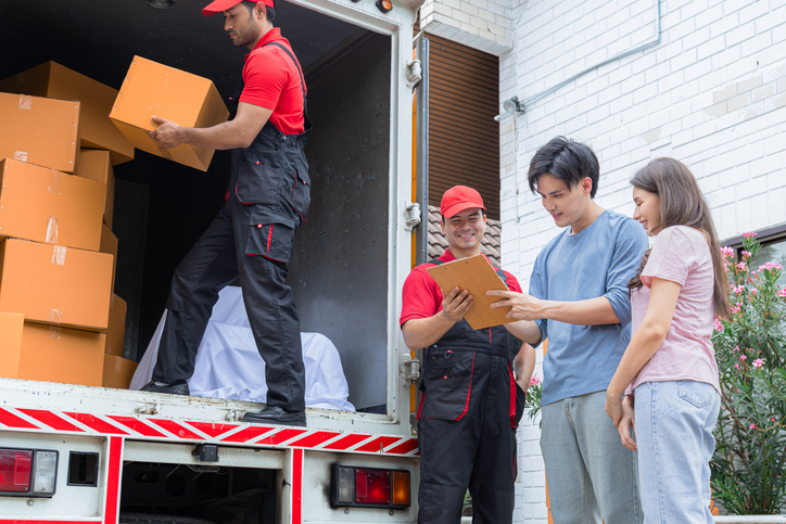 a couple signing papers next to a moving truck